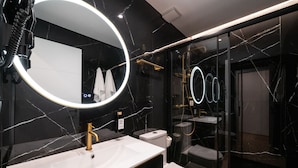 Un baño moderno con un espejo grande, un grifo dorado y un lavabo blanco.