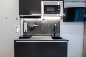 Une cuisine moderne équipée d’un four à micro-ondes encastré, d’une hotte en acier inoxydable, d’un évier et d’un plan de travail agrémenté d’un bloc à couteaux.