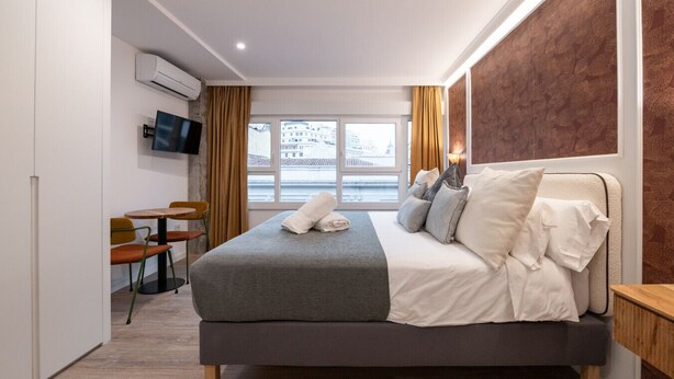A modern hotel room with a large bed, a desk, and a TV. - 306 — SB20 Boutique Studios | 1BR | 1BA | W/K (Madrid)