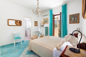 Ein Schlafzimmer mit einem großen Bett, einem Sessel, einem Schminktisch und einem Kronleuchter.