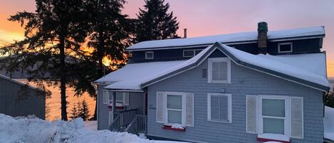 A two-story house with a snow-covered roof and a visible chimney.