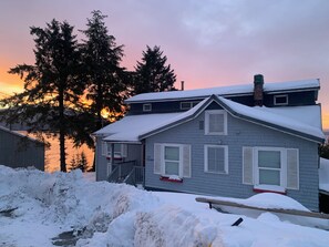 Een huis met twee verdiepingen, een sneeuwbedekte kap en een zichtbare schoorsteen.