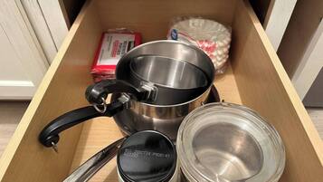 Un cajón con una olla de acero inoxidable, un frasco de vidrio y una bolsa de plástico.