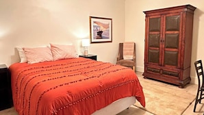 Un dormitorio con una cama grande, un aparador de madera y un cuadro en la pared.