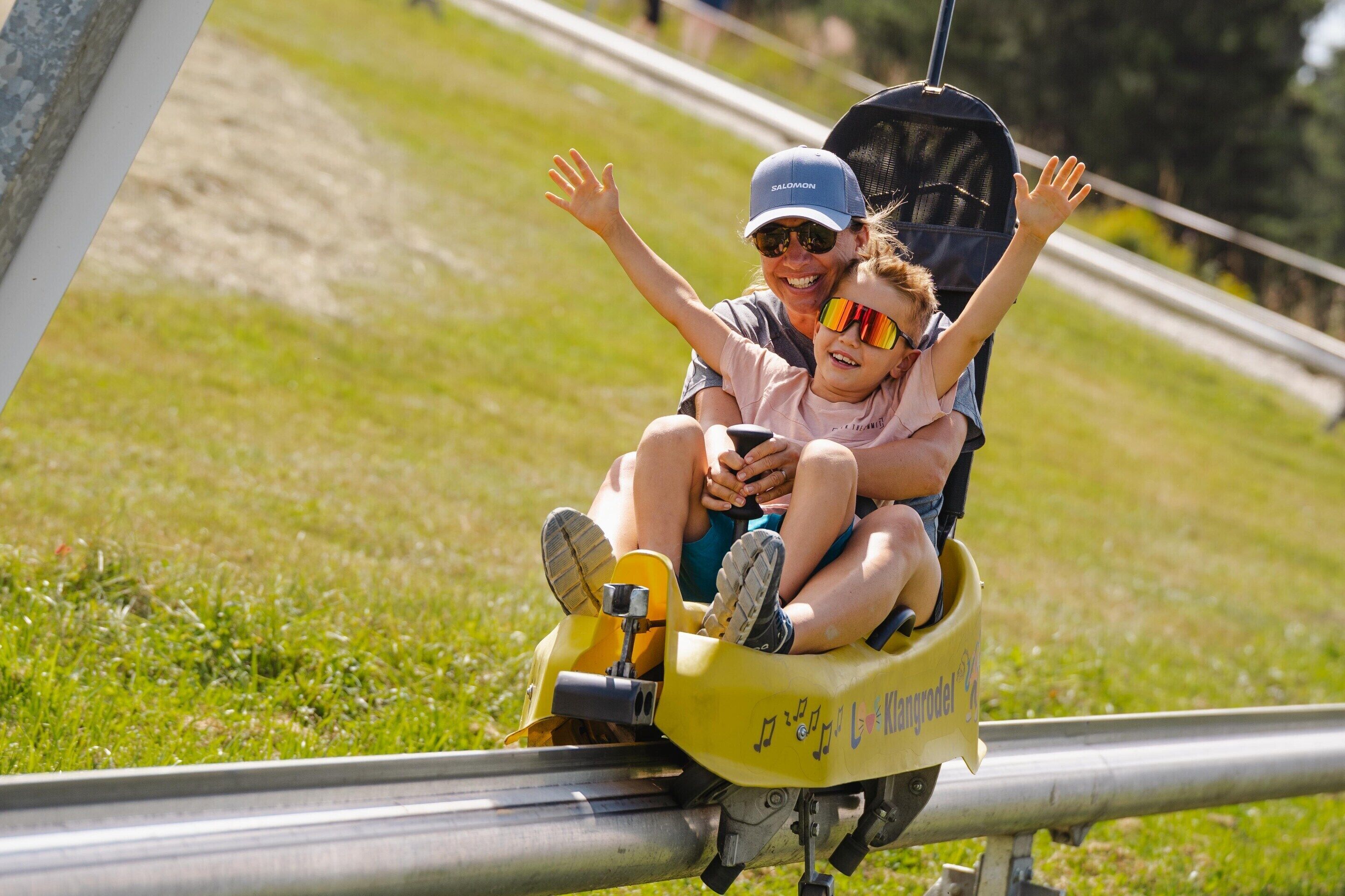 A child and an adult in a yellow amusement ride at a park.