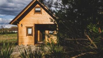 A wooden cabin with a pitched roof, a small window, and a door.