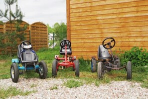 Három fűnyíró parkol egy faépület előtt.