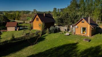 A rural property with two wooden houses, a fenced yard, and a pond.