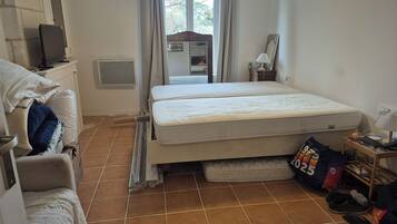 Un dormitorio con cama, escritorio, silla, televisor y ventana con cortinas.