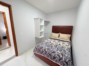 A bedroom with a bed, a white wall-mounted shelf, and a door leading to another room. - Residencia Gran Coyula Orange 506B (Tonala)