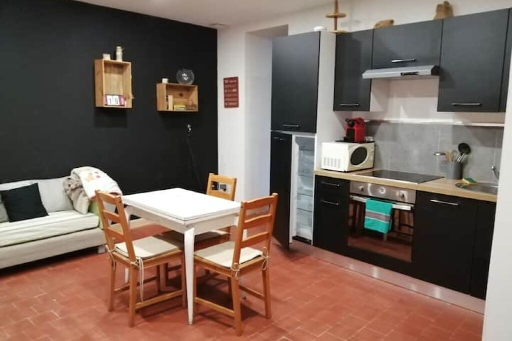 A compact kitchen with a dining area, a microwave, a stove, and a small refrigerator.