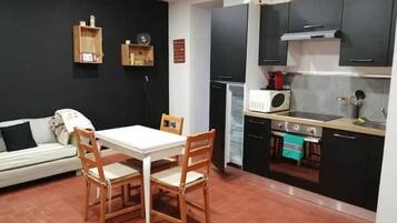 A compact kitchen with a dining area, a microwave, a stove, and a small refrigerator.