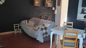 A room with a bed, a small table, a chair, a lamp, and a shelf with books. - Whole house in town, pets welcome (Caudry)