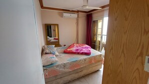 A bedroom with a bed, a ceiling fan, a mirror, and a sliding glass door to the outside.