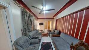 A living room with two sofas, a ceiling fan, a wooden side table, and a patterned rug.