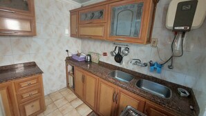 A kitchen with wooden cabinets, a granite countertop, a stainless steel sink, and a gas stove.