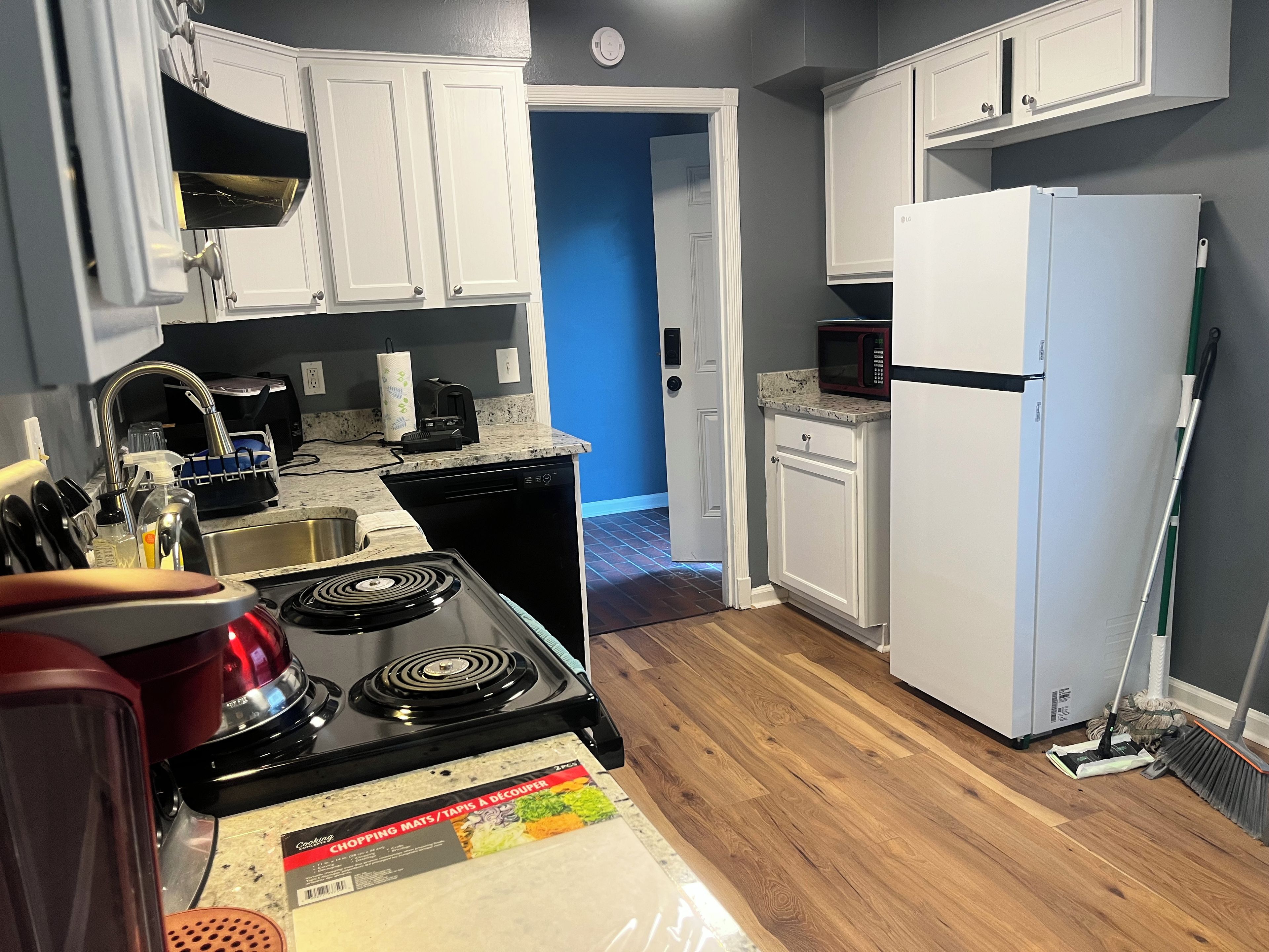 A kitchen with white cabinets, a black stove, a microwave, and a refrigerator.