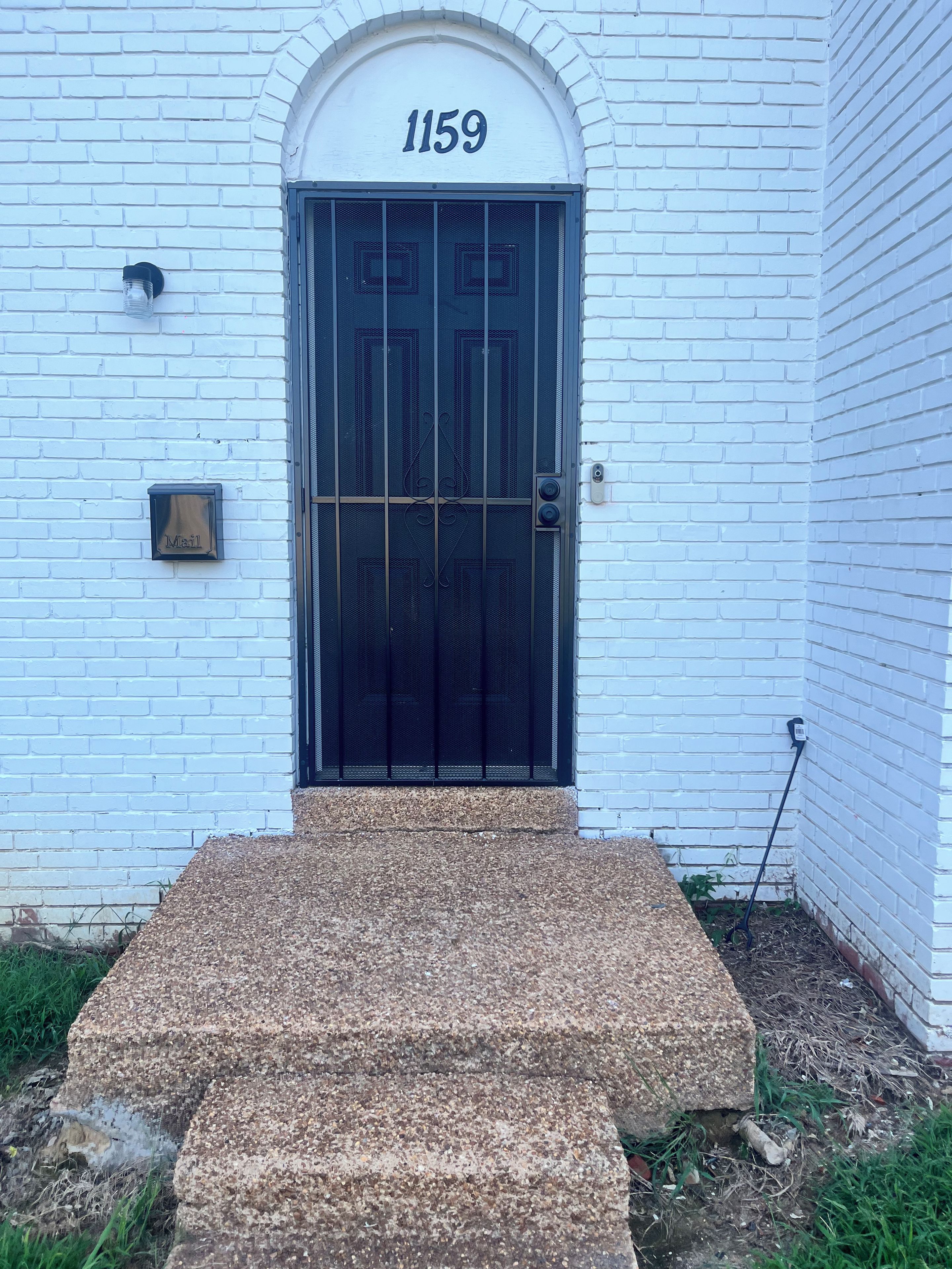 A white building with a black door and the number 1159 above it.