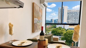 Mesa posta com pratos, guardanapos e uma garrafa de vinho, com vista para a cidade através de uma grande janela.