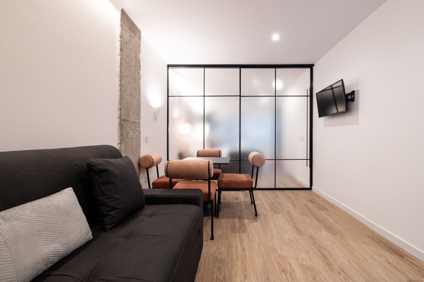 Ein modernes Wohnzimmer mit einer dunklen Couch, einem Couchtisch und einem Essbereich mit Stühlen.