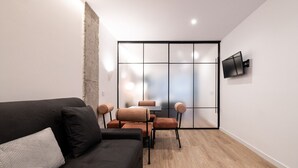Ein modernes Wohnzimmer mit einer dunklen Couch, einem Couchtisch und einem Essbereich mit Stühlen.