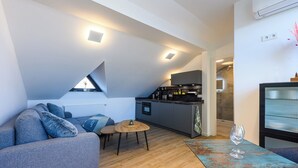 Un espacio habitable compacto con un sofá, una mesita redonda y una zona de cocina.