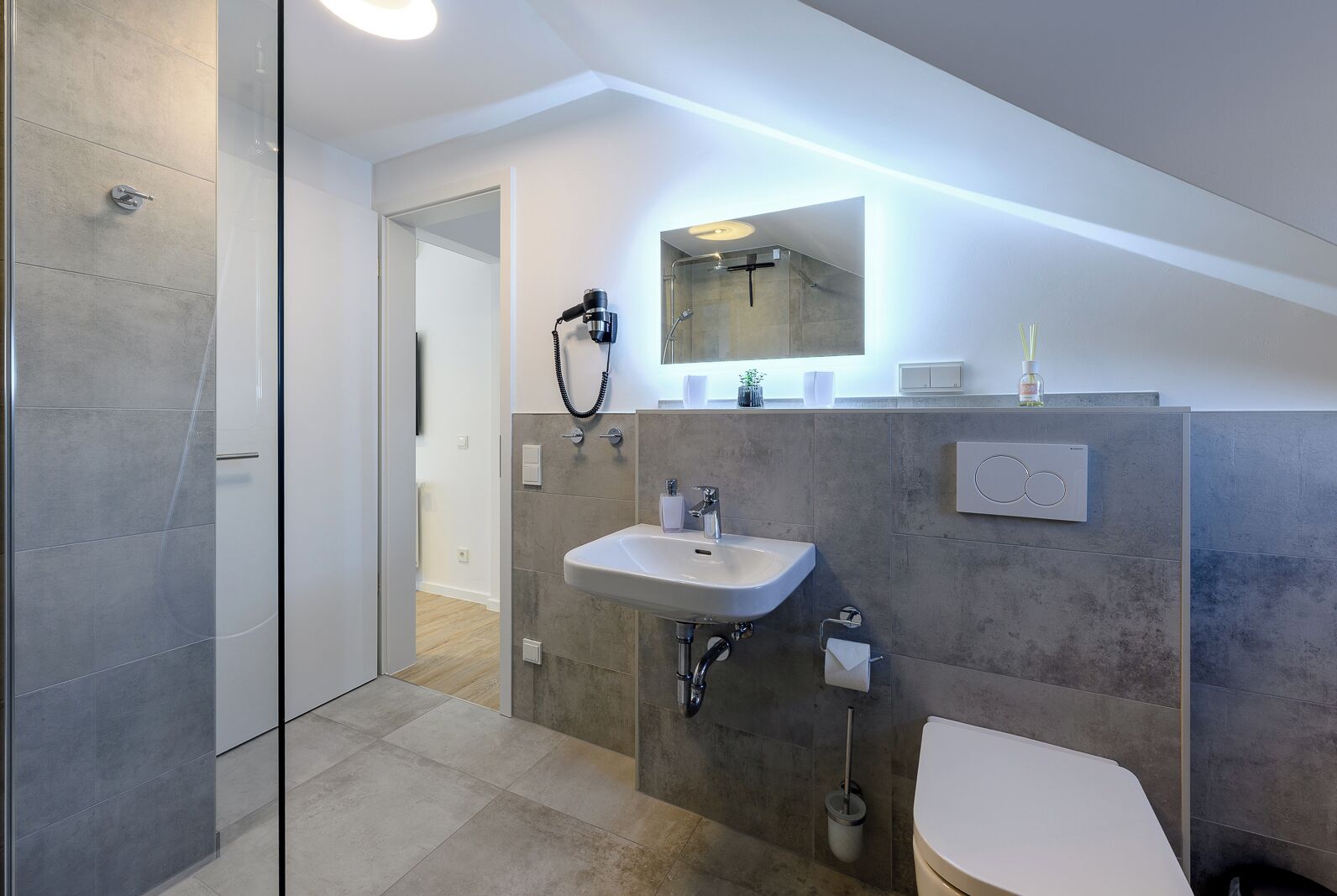 Un baño moderno con cabina de ducha de vidrio, un lavabo con espejo y un inodoro.
