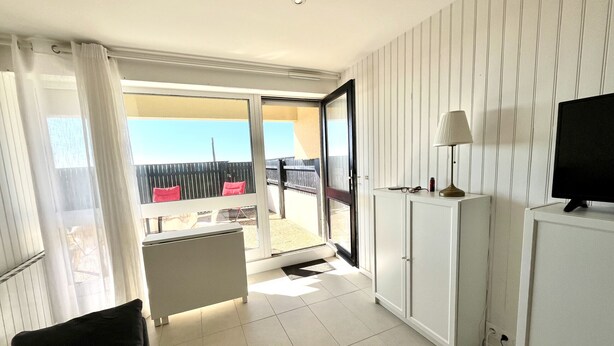 Et moderne hotelværelse med balkon, sofa, skab og fjernsyn.