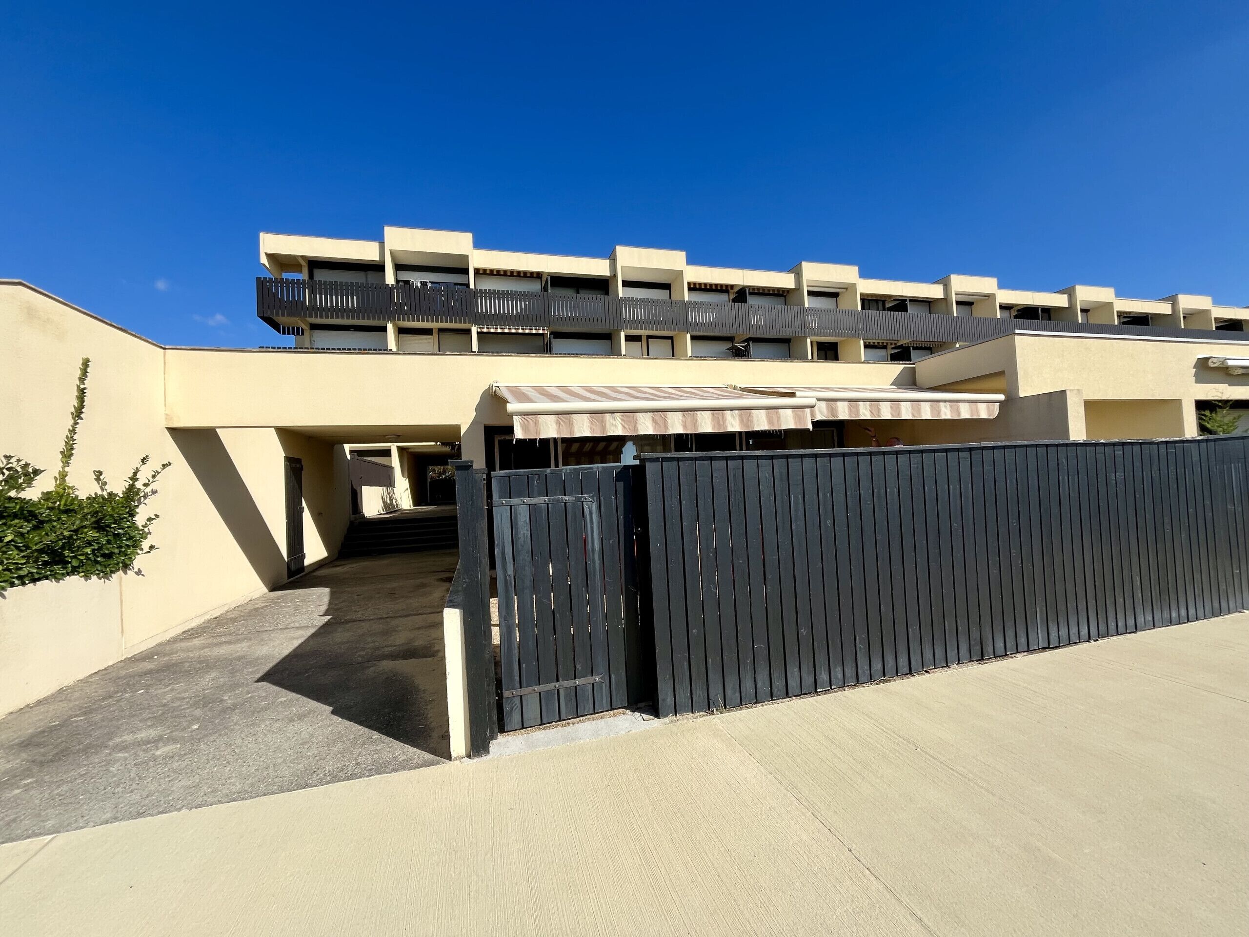 Een modern gebouw met een hekpoort, een overdekte doorgang en een plat dak.