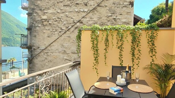 Ein Balkon mit Tisch für zwei Personen, einer Champagnerflasche und Kerzen.