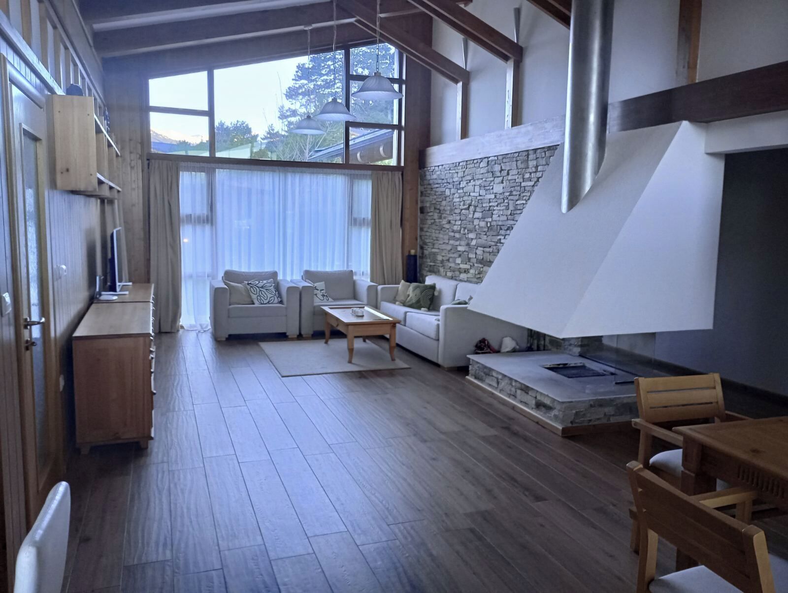 A modern living room with a stone accent wall, wooden flooring, and a built-in fireplace.