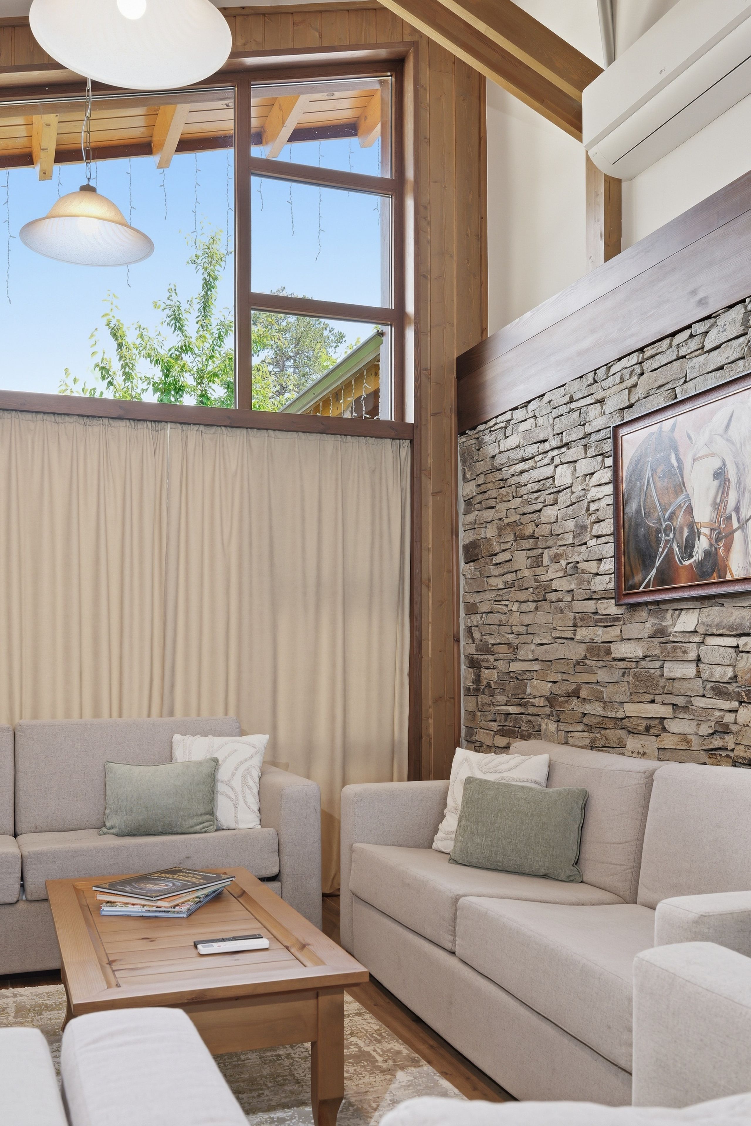 A living room with a stone wall, two sofas, a coffee table, and a hanging light fixture.