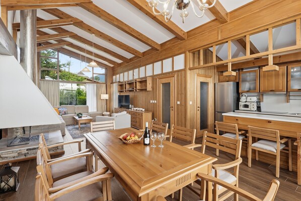 A spacious kitchen with wooden cabinetry, a dining area with a wooden table and chairs, and a large window providing natural light.