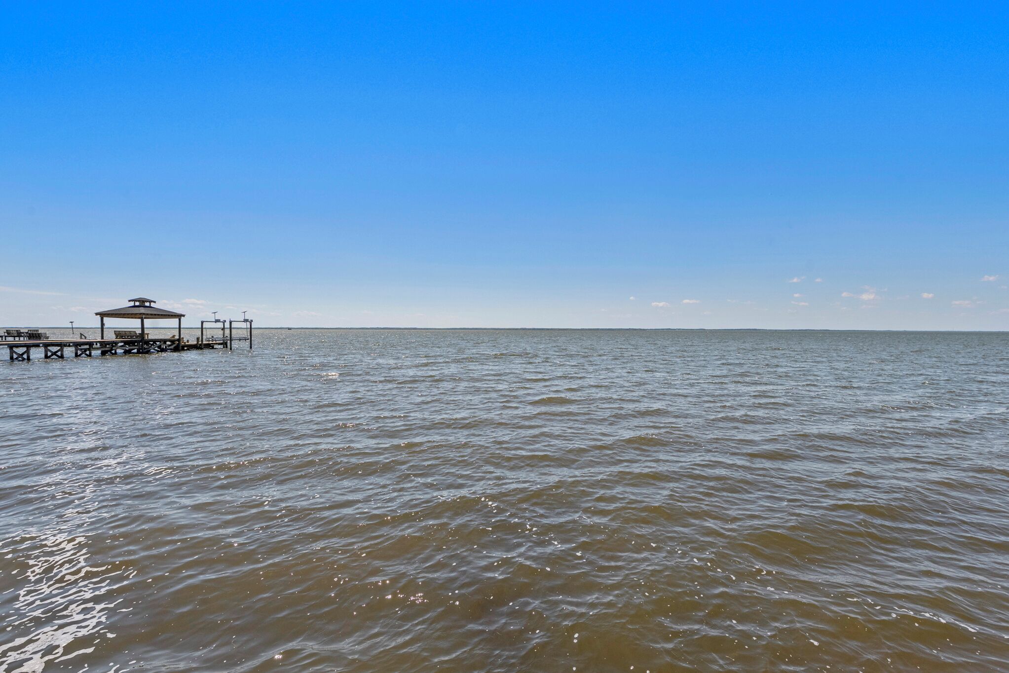 A pier extending into calm waters with a gazebo structure at the end.
