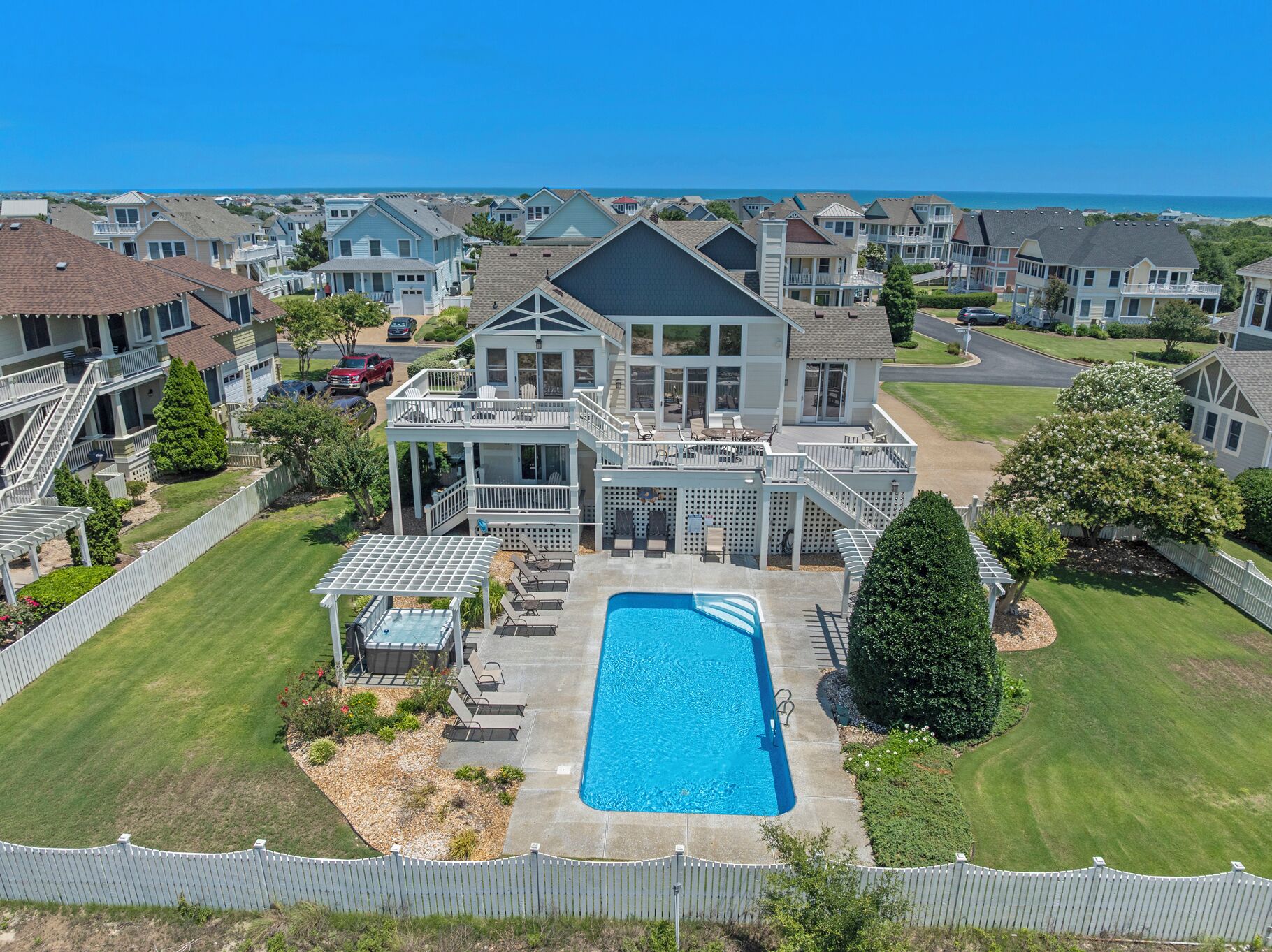 A residential property with a swimming pool, a covered patio, and a view of the ocean.