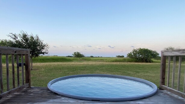A wooden deck with a circular pool in the center.