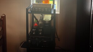A kitchen with a coffee station, a stove, and a window with a stained glass design.