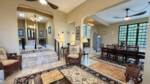 A spacious living room with a fireplace, a dining area with wooden chairs, and a staircase leading to an upper level. - Vieques BioBay Bed and Breakfast (Vieques)