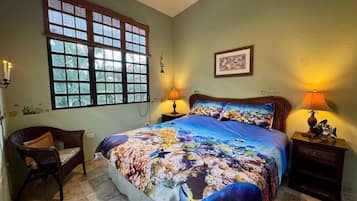 A bedroom with a bed, two bedside lamps, a chair, a window, and a framed picture on the wall.
