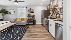 Una cocina compacta con electrodomésticos modernos, un área de comedor con sofá y un ventilador de techo.