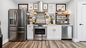 Una cocina moderna con electrodomésticos de acero inoxidable, armarios blancos y decoración en la pared.