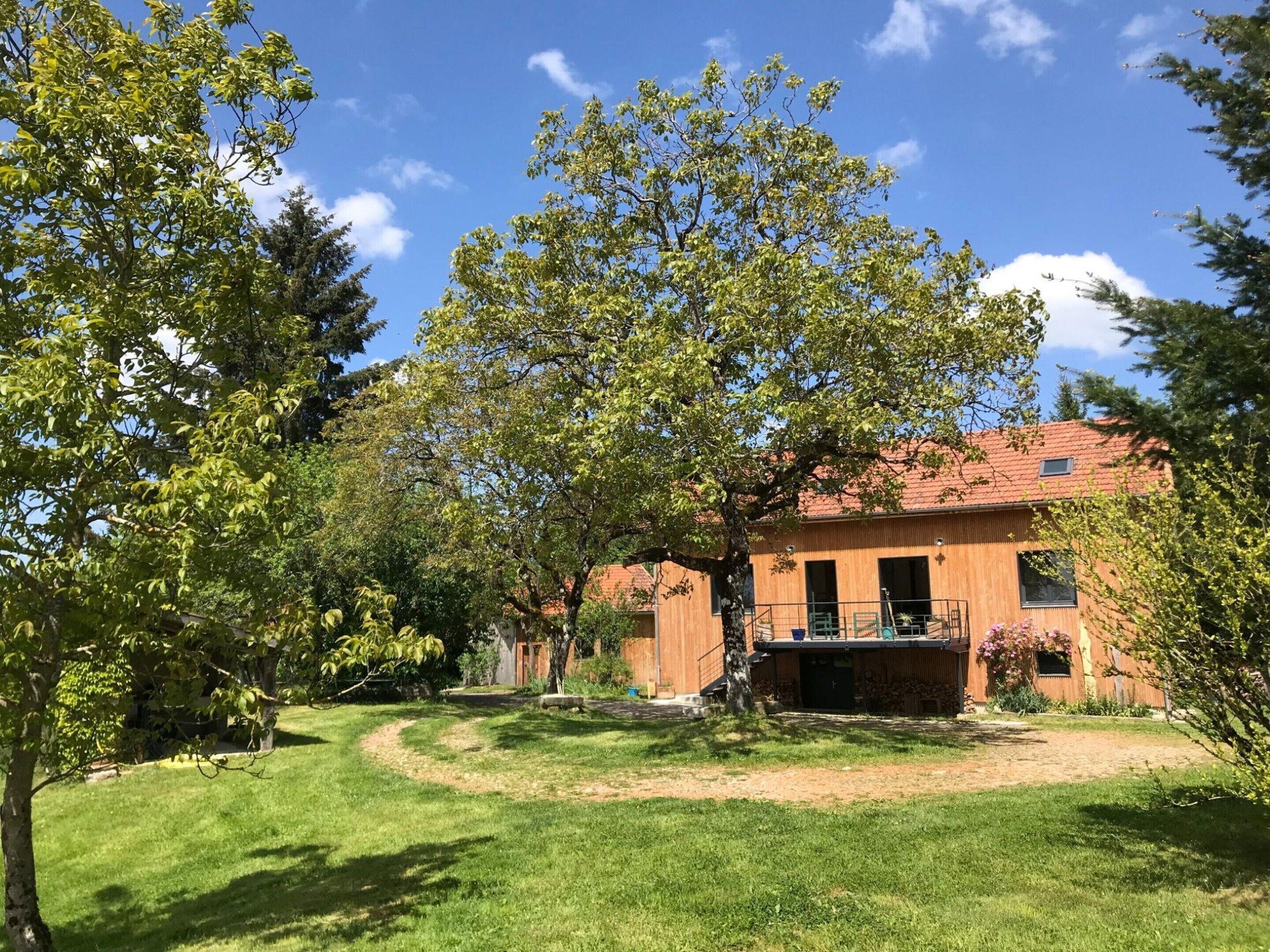 A building with a red roof, surrounded by a well-maintained lawn and trees.