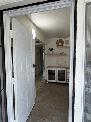 A hallway with a white door, a fan, and a cabinet with glass doors. - Vacation Home Cute 3 bed 1 bath with PLENTY OF PARKING. Cardinals Stadium (Phoenix)
