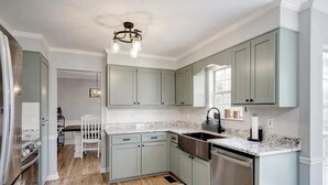 Een moderne keuken met lichtgroene kastjes, een roestvrijstalen spoelbak en een granieten werkblad.