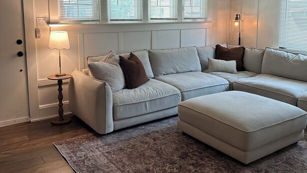 Ein Wohnzimmer mit Ecksofa, Deckenventilator und einem gemusterten Teppich.