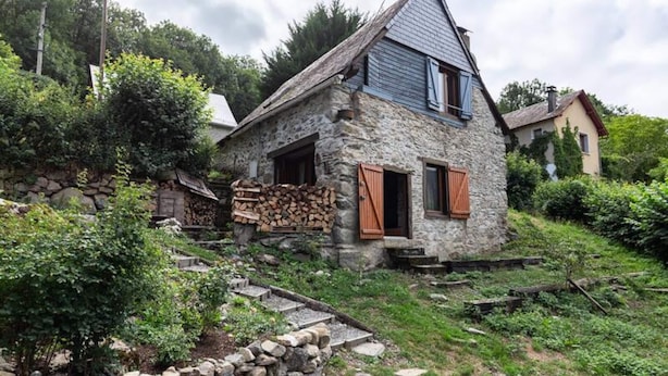 A stone house with a steep roof, wooden shutters, and a stone staircase leading up to the entrance. - Holiday Home in Aneran Near Peyragudes (Cazaux-Frechet-Aneran-Camors)