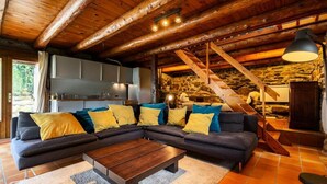 A cozy living room with a sectional sofa, a wooden coffee table, and a stone wall. - Holiday Home in Aneran Near Peyragudes (Cazaux-Frechet-Aneran-Camors)