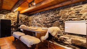A rustic kitchen with stone walls, wooden beams, a wooden table set for dining, and a white refrigerator. - Holiday Home in Aneran Near Peyragudes (Cazaux-Frechet-Aneran-Camors)
