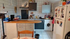 A compact kitchen with a washing machine, a sink, and a wooden countertop. - Small house located in a village 15min from Langeais (Hommes)