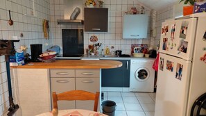 Eine kleine Küche mit Waschmaschine, Spüle und einer Holzarbeitsplatte.